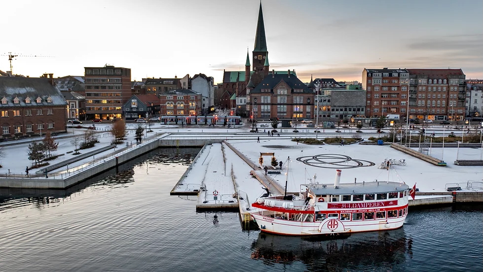 Image of the ship 'Juldamperen' in the ocean with Aarhus city in the background.